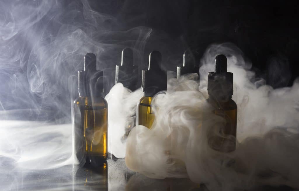 Glass bottles with pipettes and VAPE liquid. Thick vapor from Smoking an electronic cigarette.