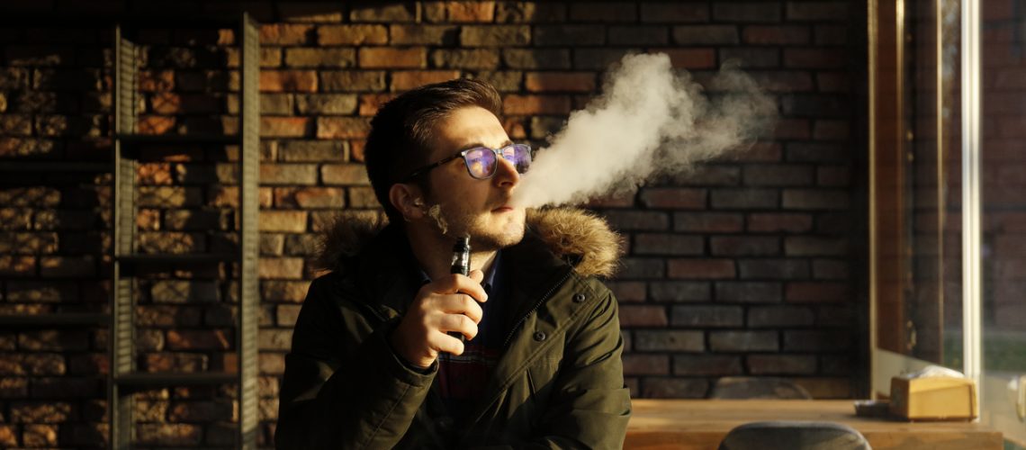 The man smoke an electronic cigarette at the cafe